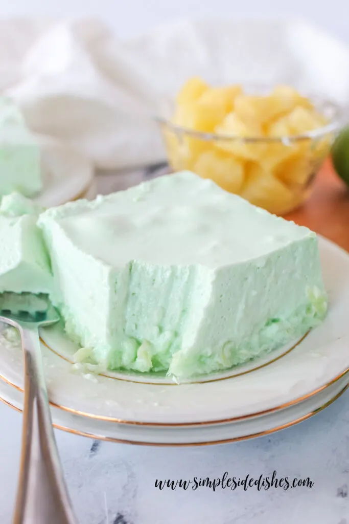 Square of Jello on a plate with a fork portion removed.