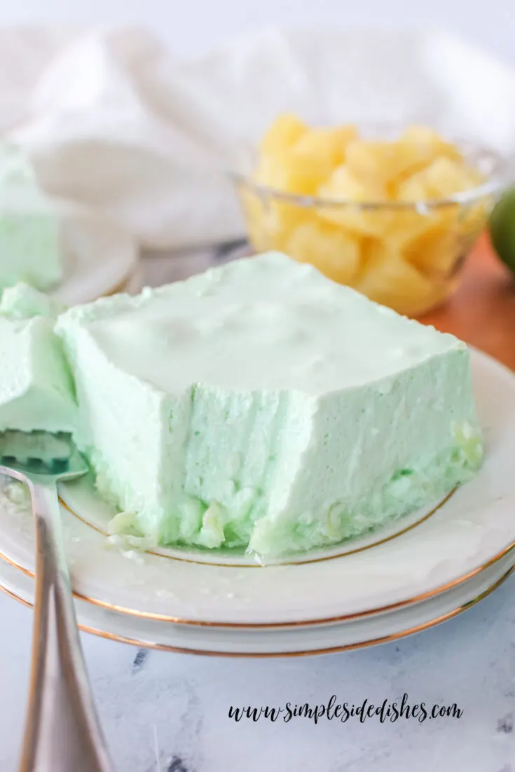 Square of Jello on a plate with a fork portion removed.