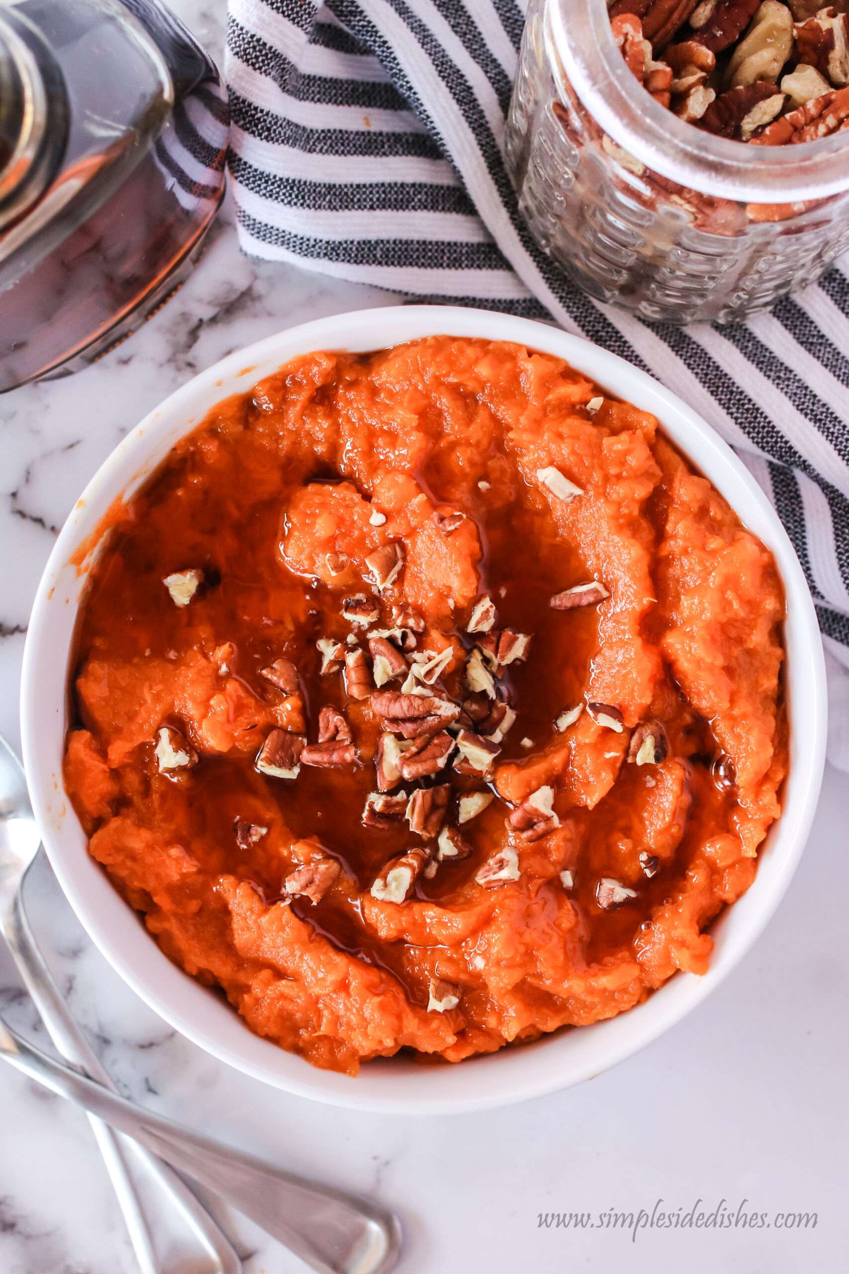 Pecans sprinkled on top of mashed sweet potatoes and maple syrup