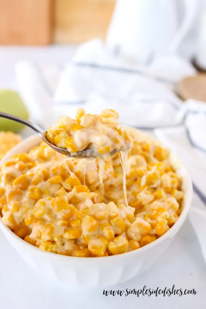 side view of cream corn in a dish with a spoonful portion being removed - shows cheese pull.