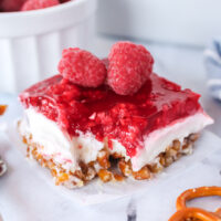 slice of raspberry pretzel salad on a plate with a forkful missing.