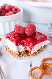 slice of raspberry pretzel salad on a plate with a forkful missing.