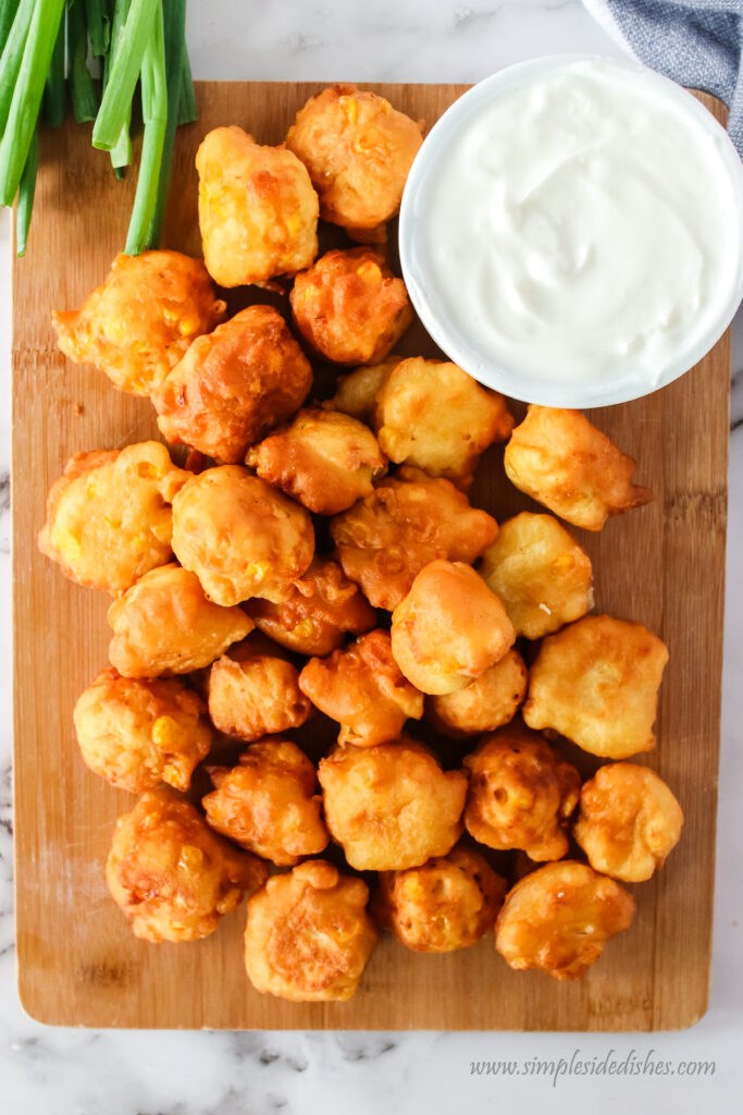 top view looking down of fritters on a serving board with sour cream dip.