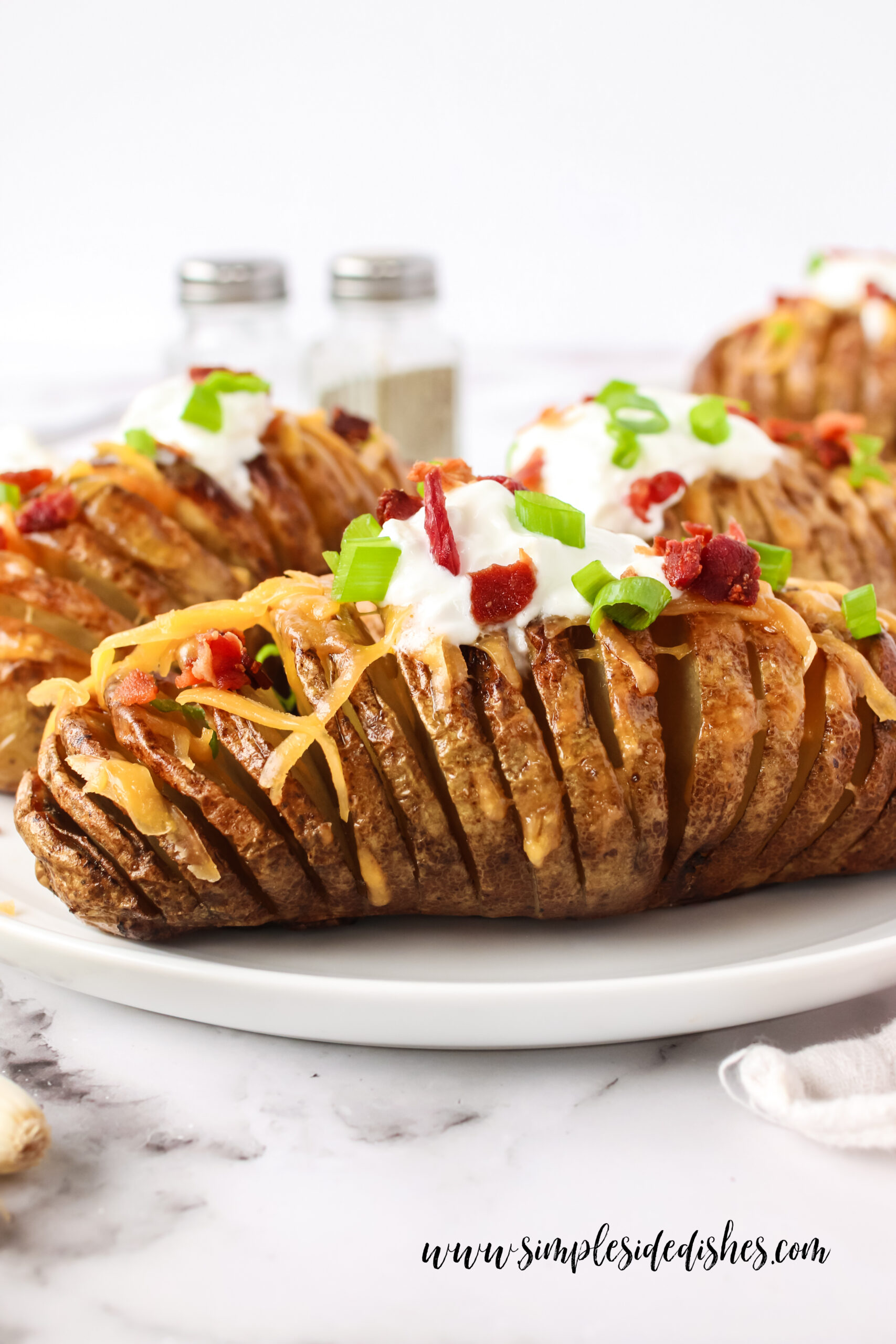 side view of potatoes on a plate, fully loaded and ready to eat.