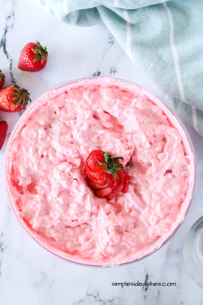 zoomed out image of jello fluff in serving bowl with a sliced strawberry on top