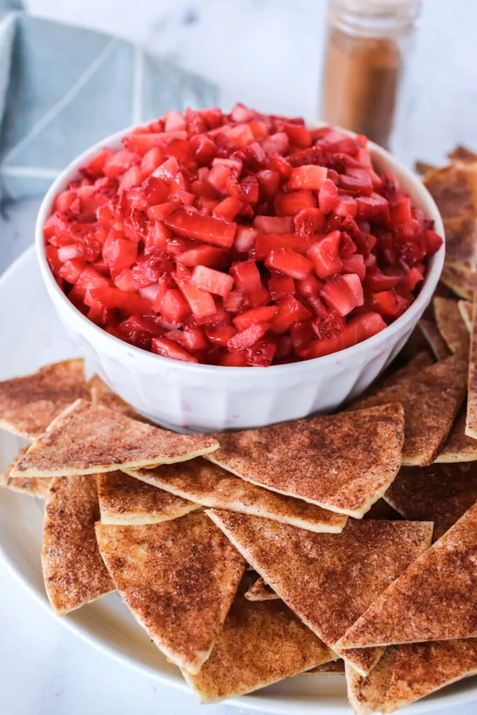 side view of cinnamon sugar tortilla chips and a bowl of strawberries