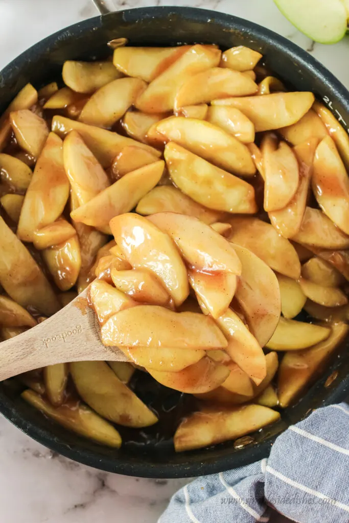 fried apples in skillet with wooden spoon. Photo taken from the top looking down.