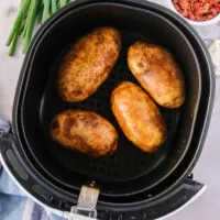 4 potatoes placed into air fryer basket, ready to cook