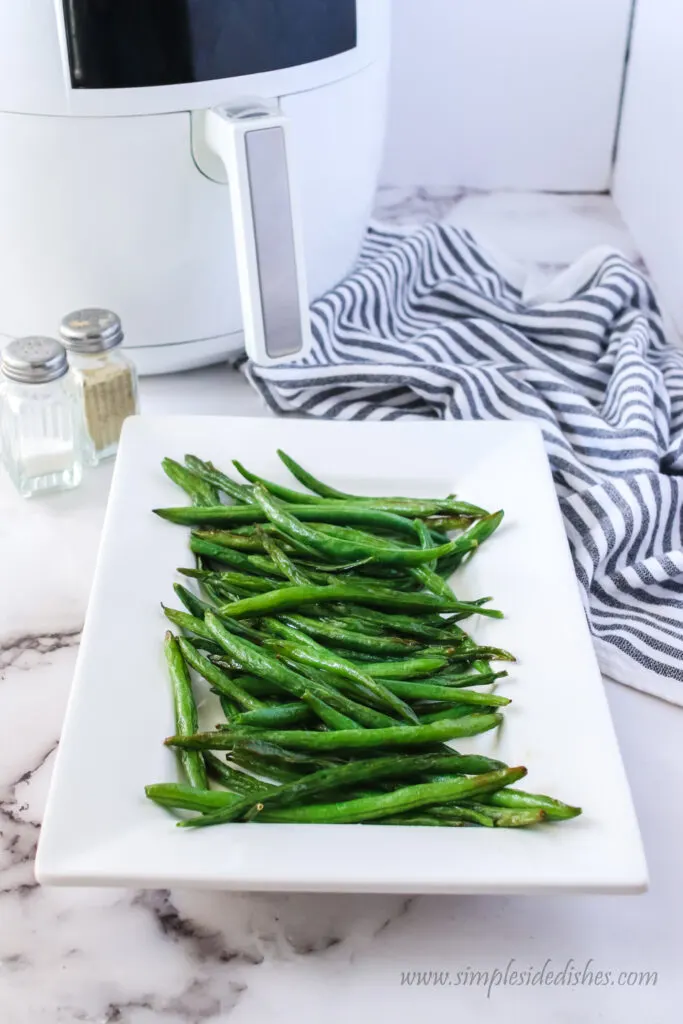 zoomed out image of green beans with air fryer in background