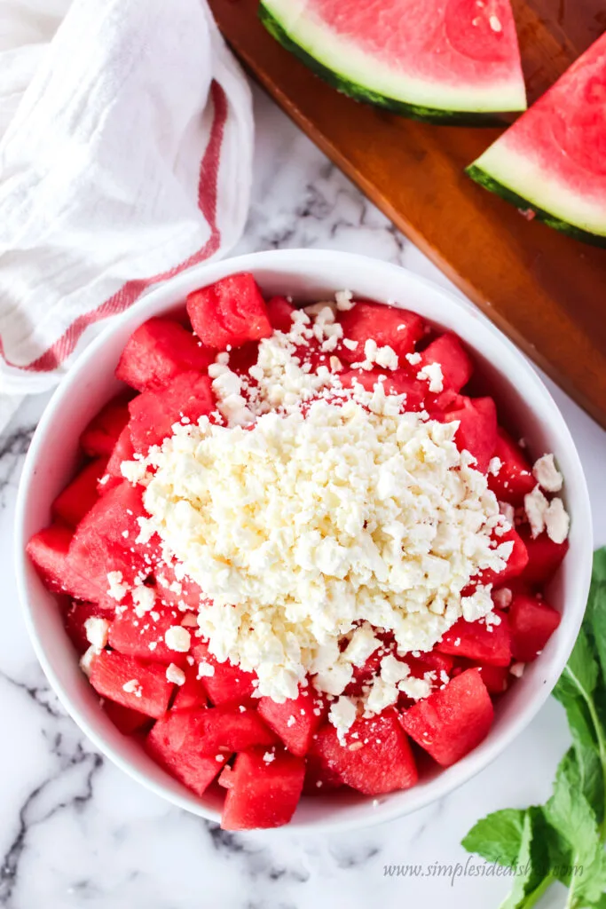 cut watermelon and feta cheese added to a large bowl