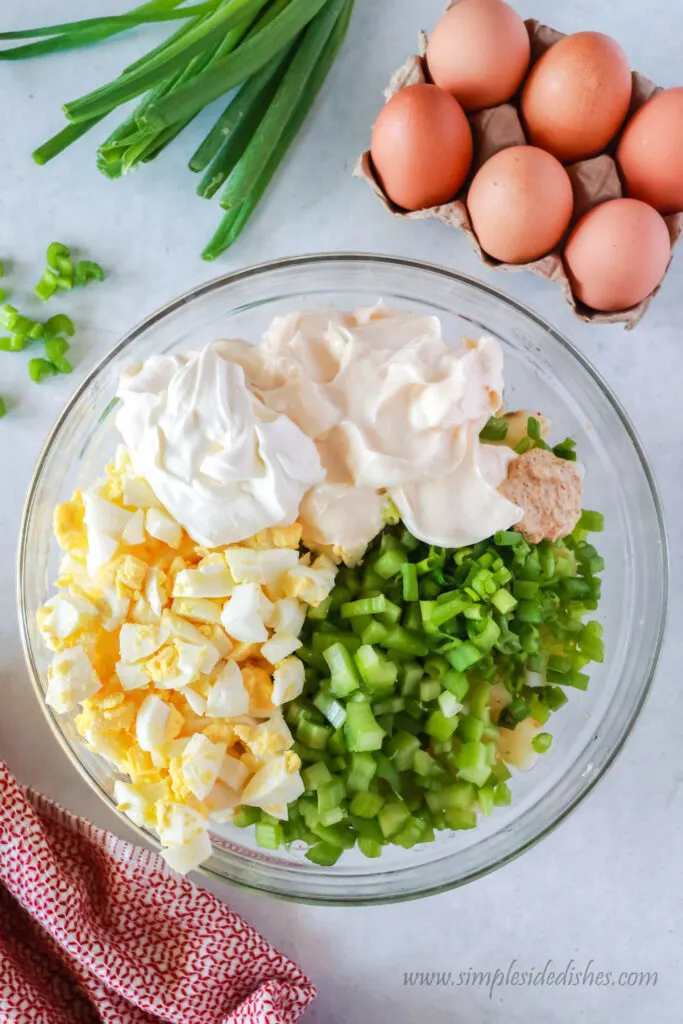 celery, green onions, eggs, mayonnaise, sour cream and mustard added to bowl