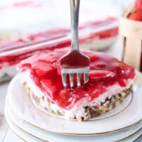 piece of jello on a stack of plates with a fork in it.