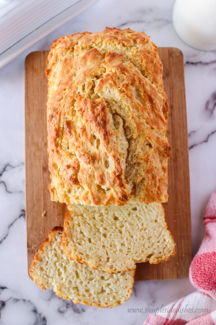 zoomed out image of bread on a cutting board with two slices cut