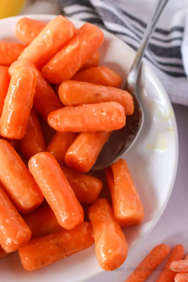 spoon scooping out carrots off of serving dish