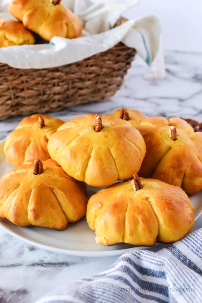 side view of pumpkin rolls on a plate with a basket full behind