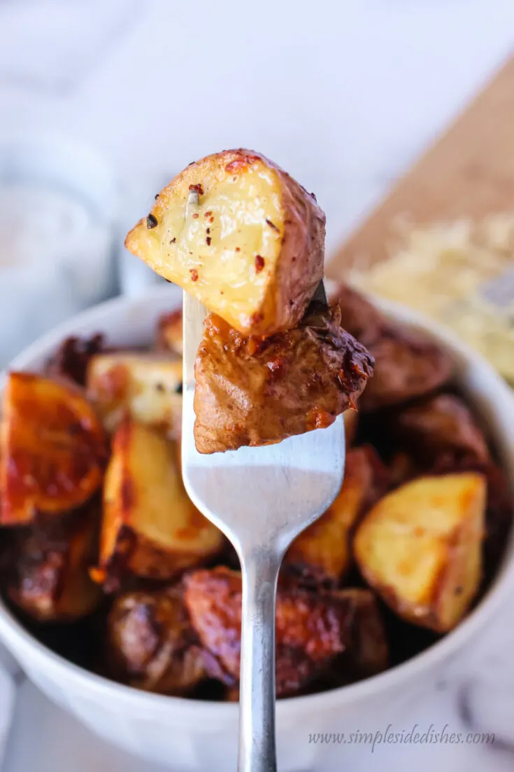 fork picking up two potatoes from bowl