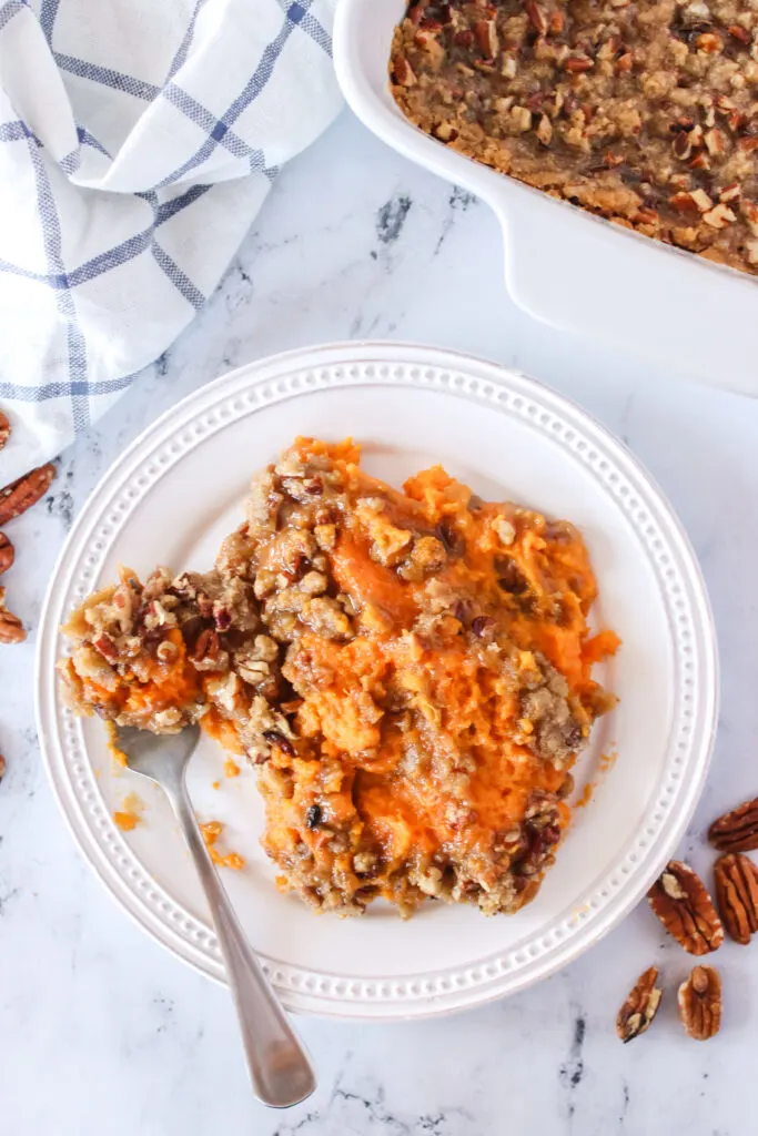 Sweet potato and pecan streusel topping casserole on a plate with fork full.