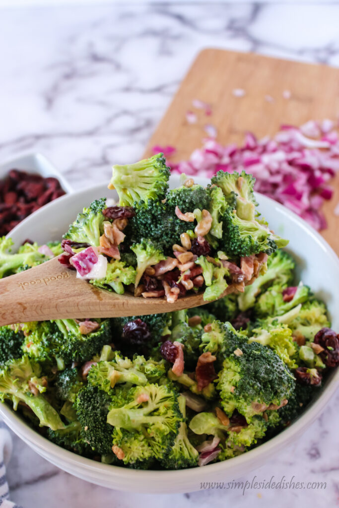 top side view of bacon broccoli salad in bowl with wooden spoon