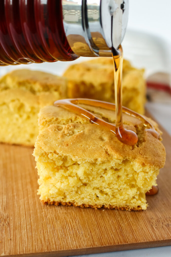 maple syrup being drizzled over the top of cornbread
