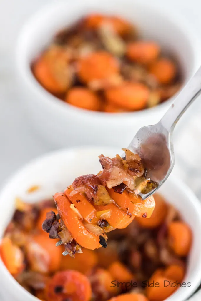 two bowls of bacon and carrots side dish. Front bowl has a fork full of mixture.