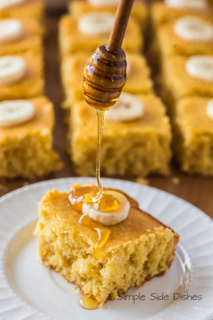 slice of cornbread on plate with honey being drizzled on top