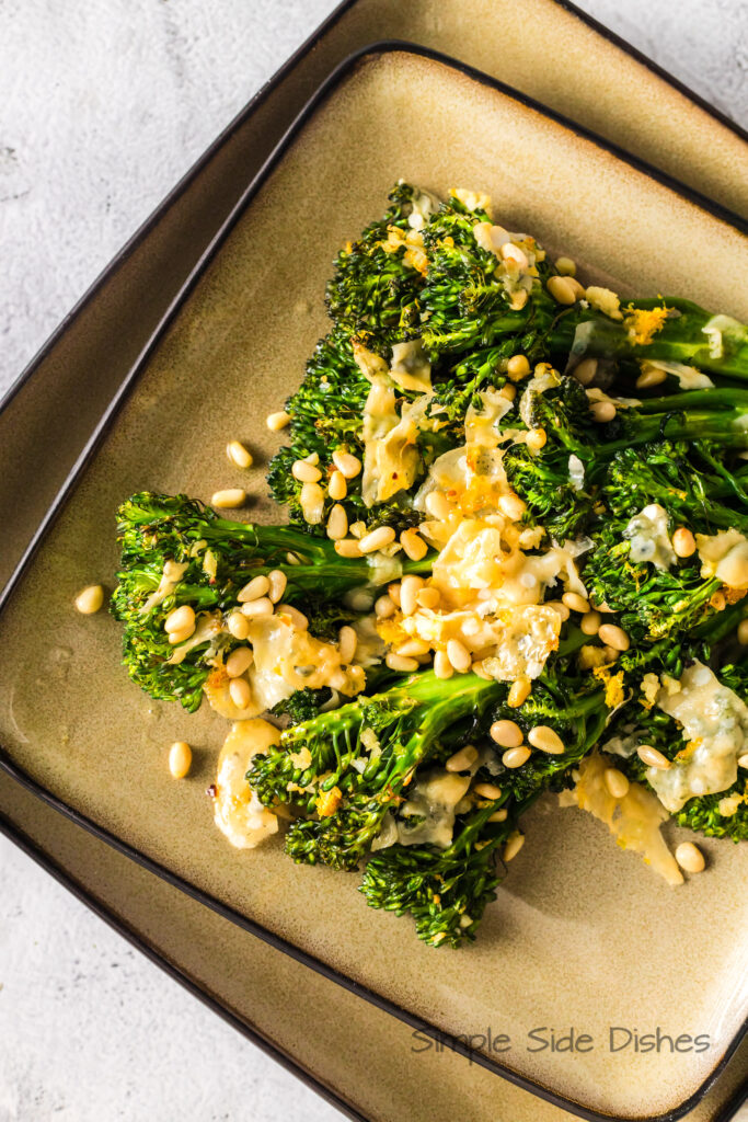 plate full of broccoli with cheese and pine nuts