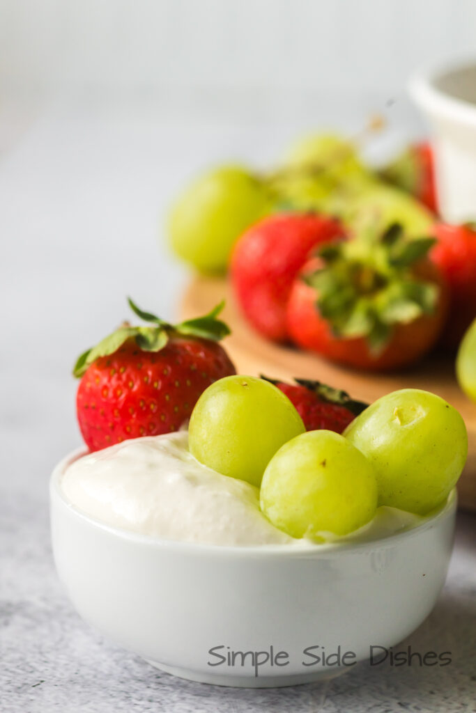 mini bowl of fruit dip with grapes and strawberries in it