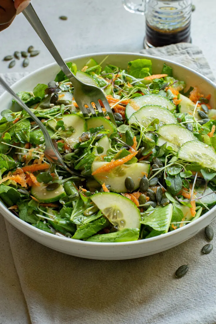 Finished salad in bowl with salad tongs scooping some out.