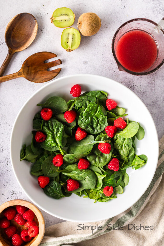spinach and raspberries in a serving bowl.