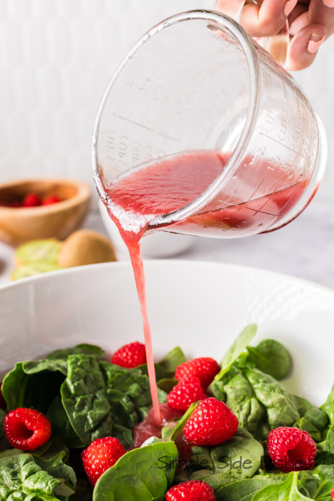salad dressing being poured on salad.