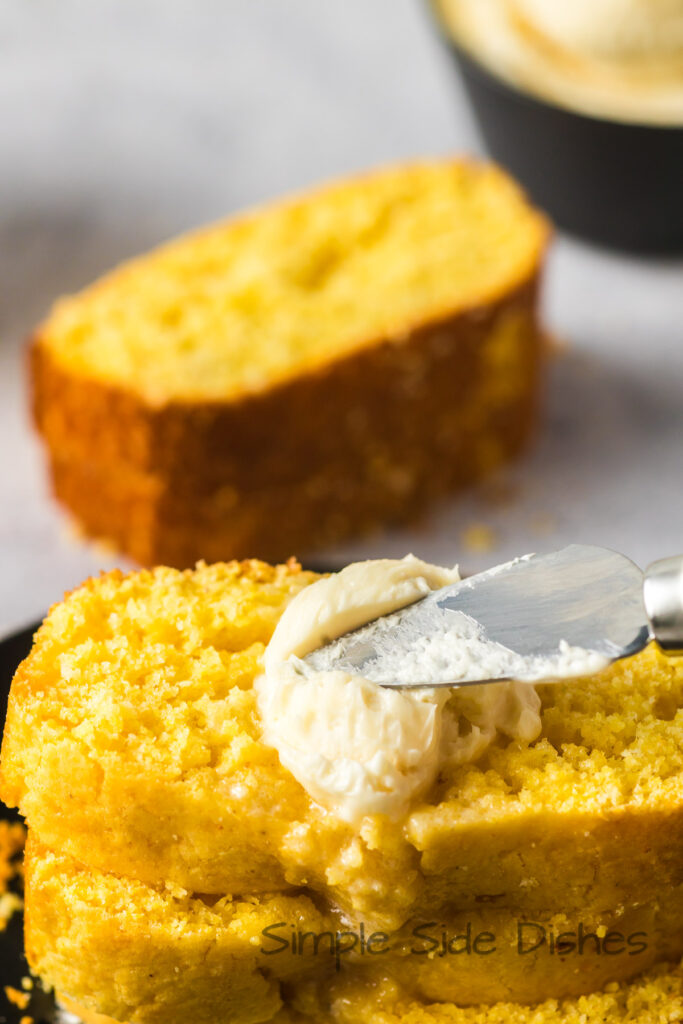 A knife spreading butter on a slice of bread.