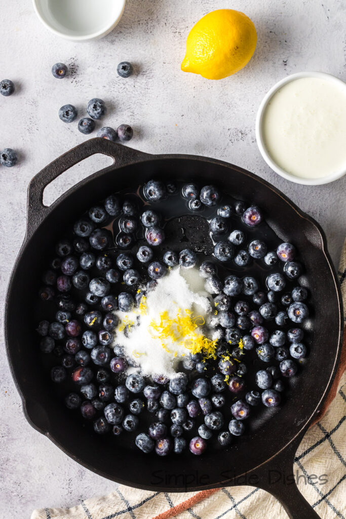 blueberries, sugar, lemon zest and lemon juice added to a skillet.