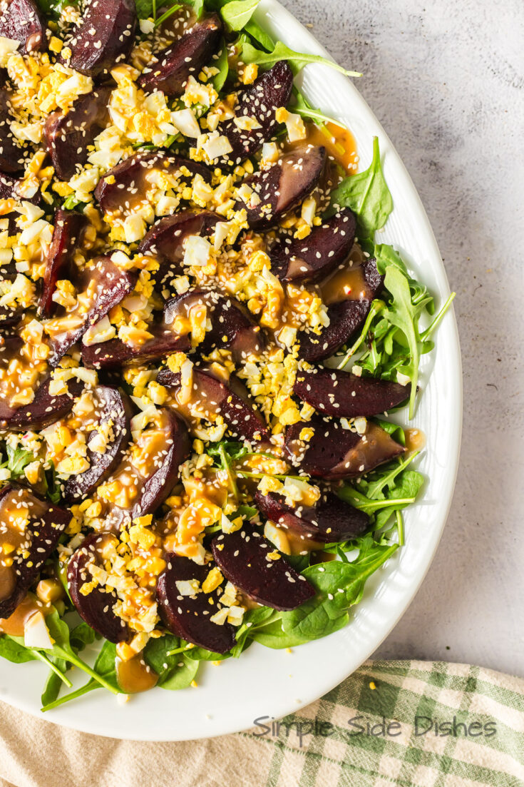 zoomed in image of the salad on a platter. Dressing, Eggs, Beets and lettuce all ready to serve.