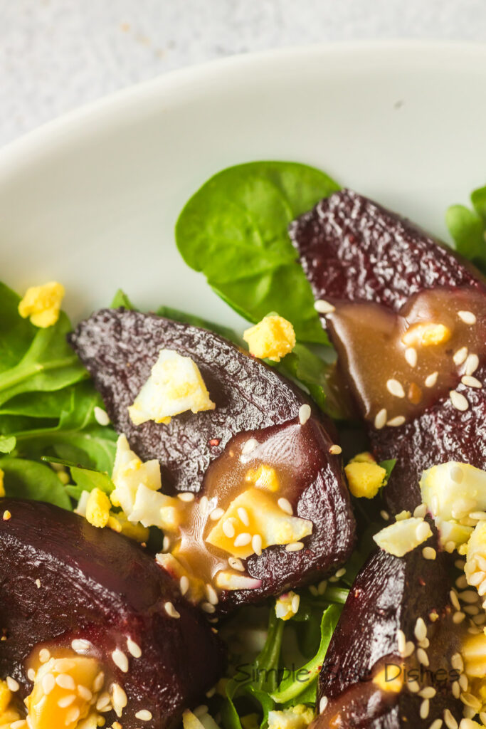 zoomed in image of beets on a bed of lettuce with dressing.