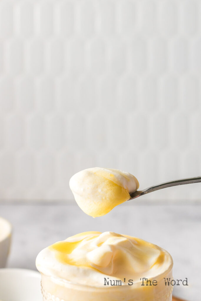 A side view of a spoon scooping some out of a cup.