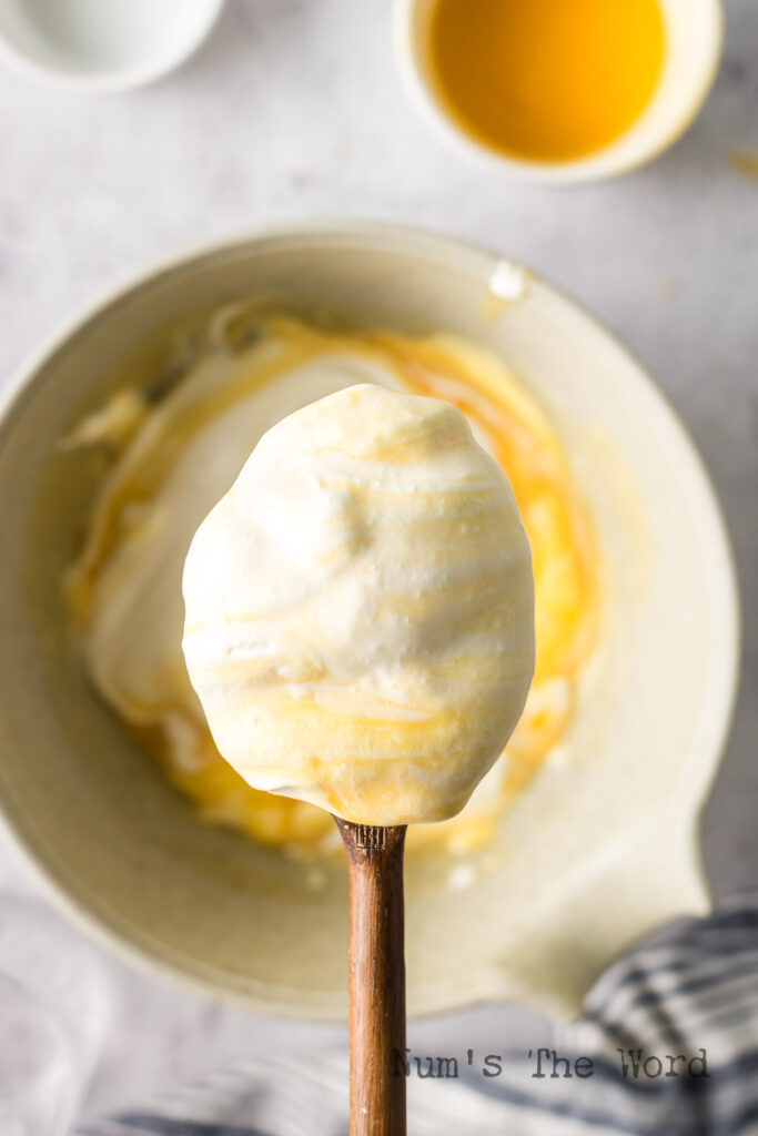 A wooden spoon scooping a portion of the fool out of the bowl.